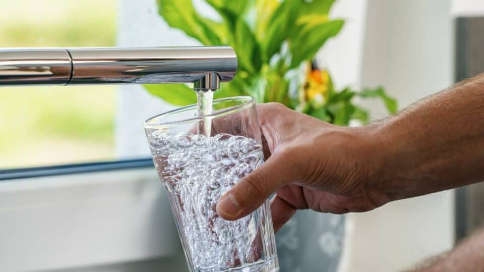 a person getting a glass of water from the tap rather than drinking bottled water 2